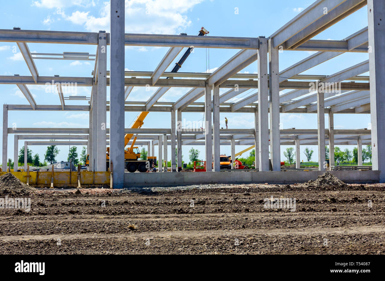 Worker is helping mobile crane to manage concrete joist for assembly ...