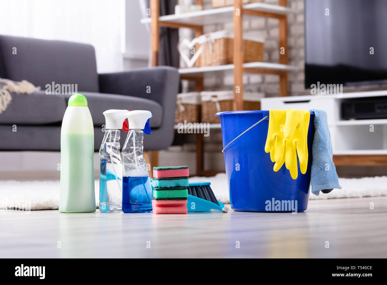 Close-up Of Cleaning Products And Tools On Hardwood Floor In Living Room Stock Photo