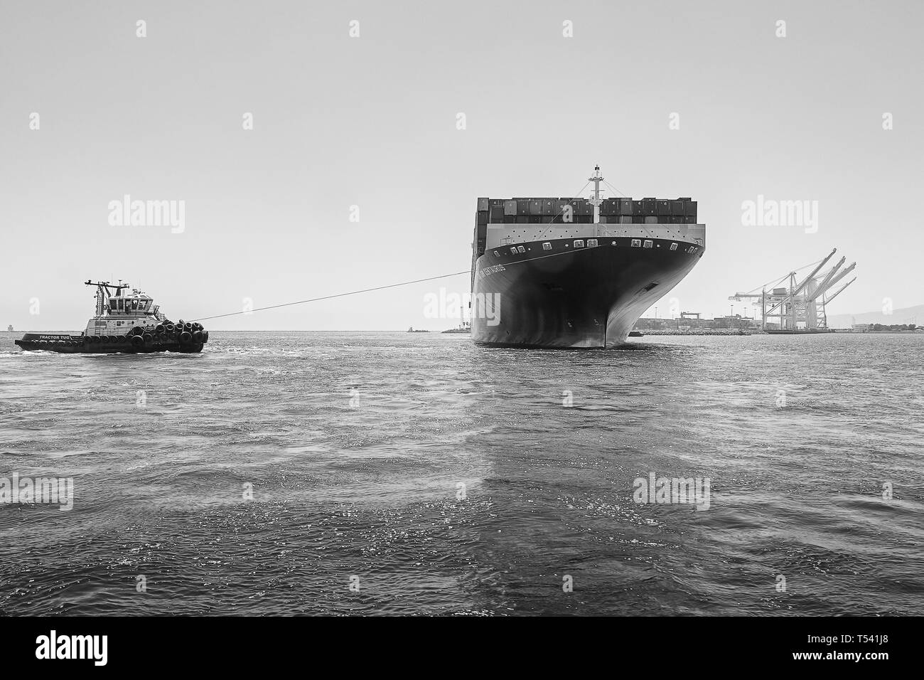 Black And White Photo Of The Container Ship, CMA CGM CENTAURUS, Being Turned Through 180 Degrees By Tug JOHN QUIGG, Before Docking In Long Beach, USA Stock Photo