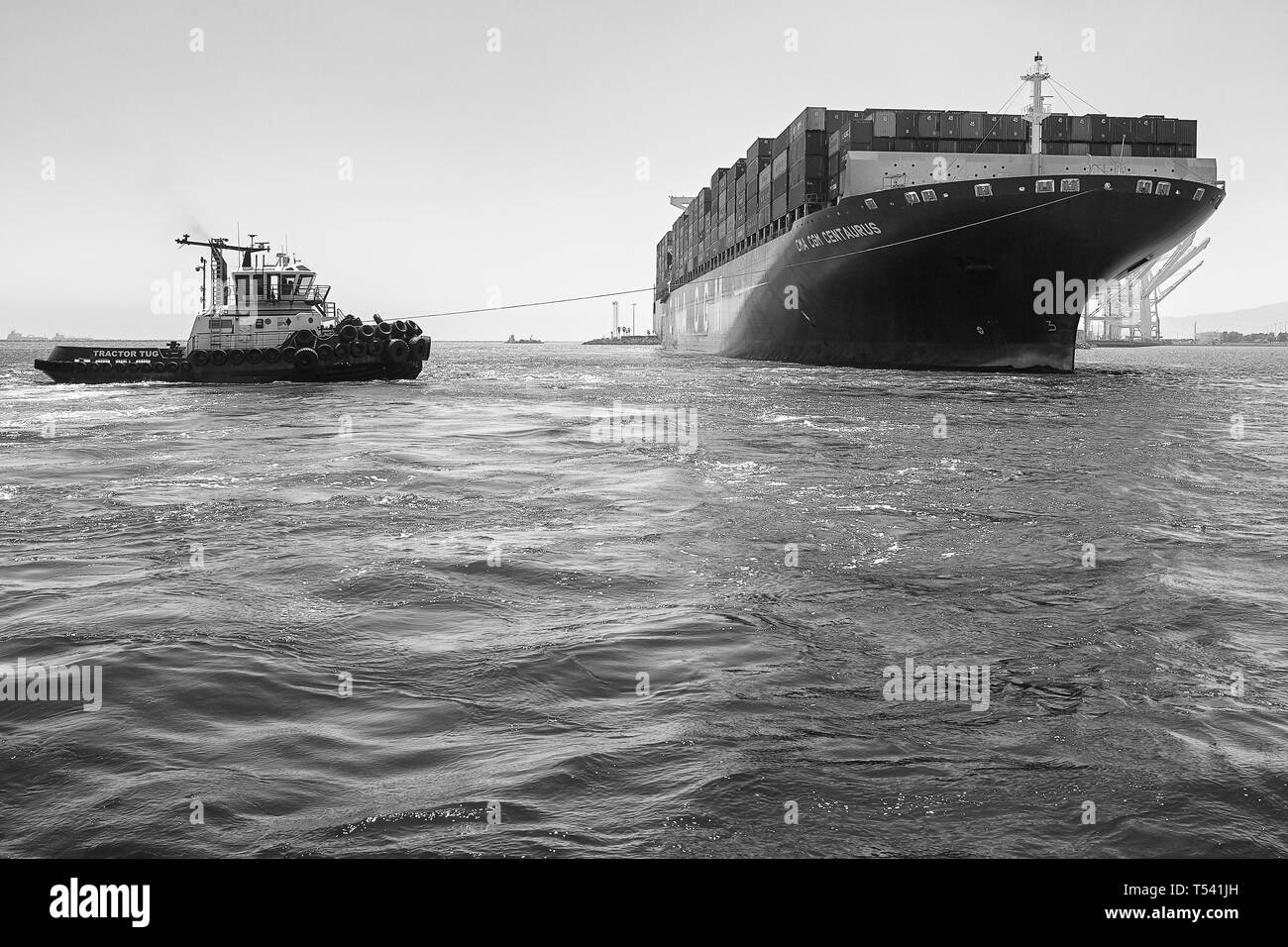 Black And White Photo Of The Container Ship, CMA CGM CENTAURUS, Being Turned Through 180 Degrees By Tug JOHN QUIGG, Before Docking In Long Beach, USA. Stock Photo
