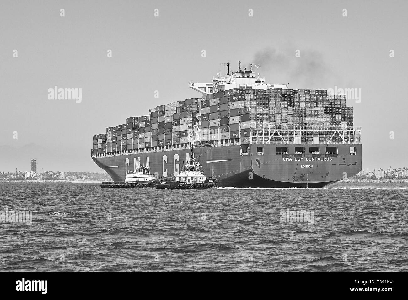 Black And White Photo Of Container Ship, CMA CGM CENTAURUS, Being Turned Through 180 Degrees By 2 Tugs Before Docking In Long Beach, California, USA Stock Photo