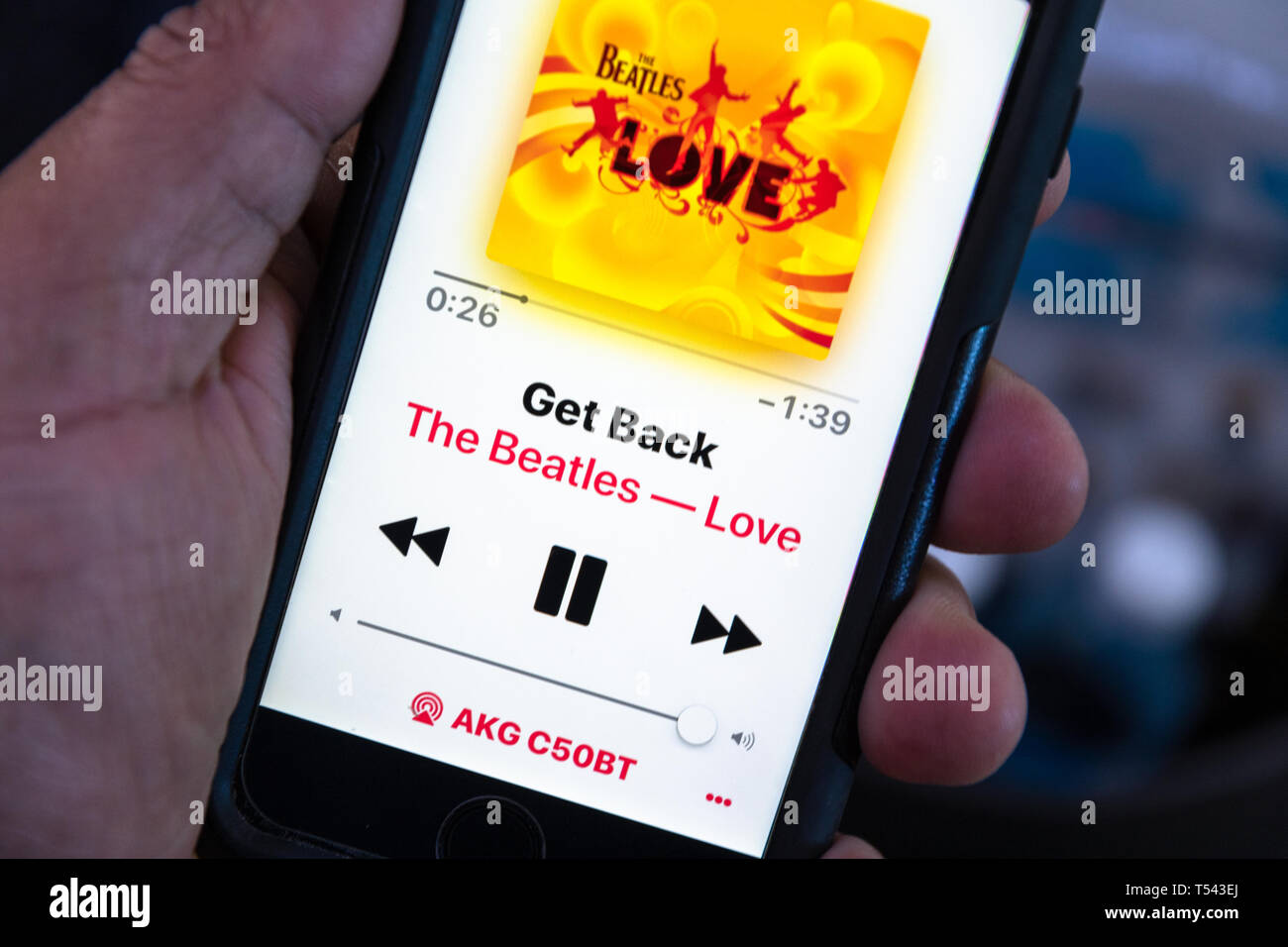 In this photo illustration, somebody listens to The Beatle's music on a smartphone. The screen shows the 'Get Back' song title and the cover of the al Stock Photo