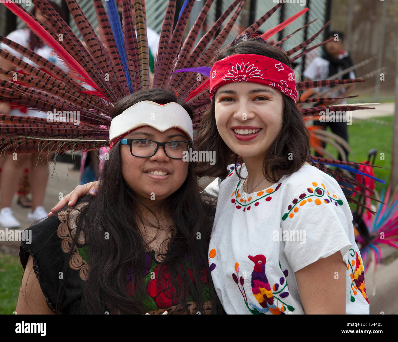 Two teens smiling in costume wearing indigenous feathered headpiece in the Cinco de Mayo Parade. St Paul Minnesota MN USA Stock Photo