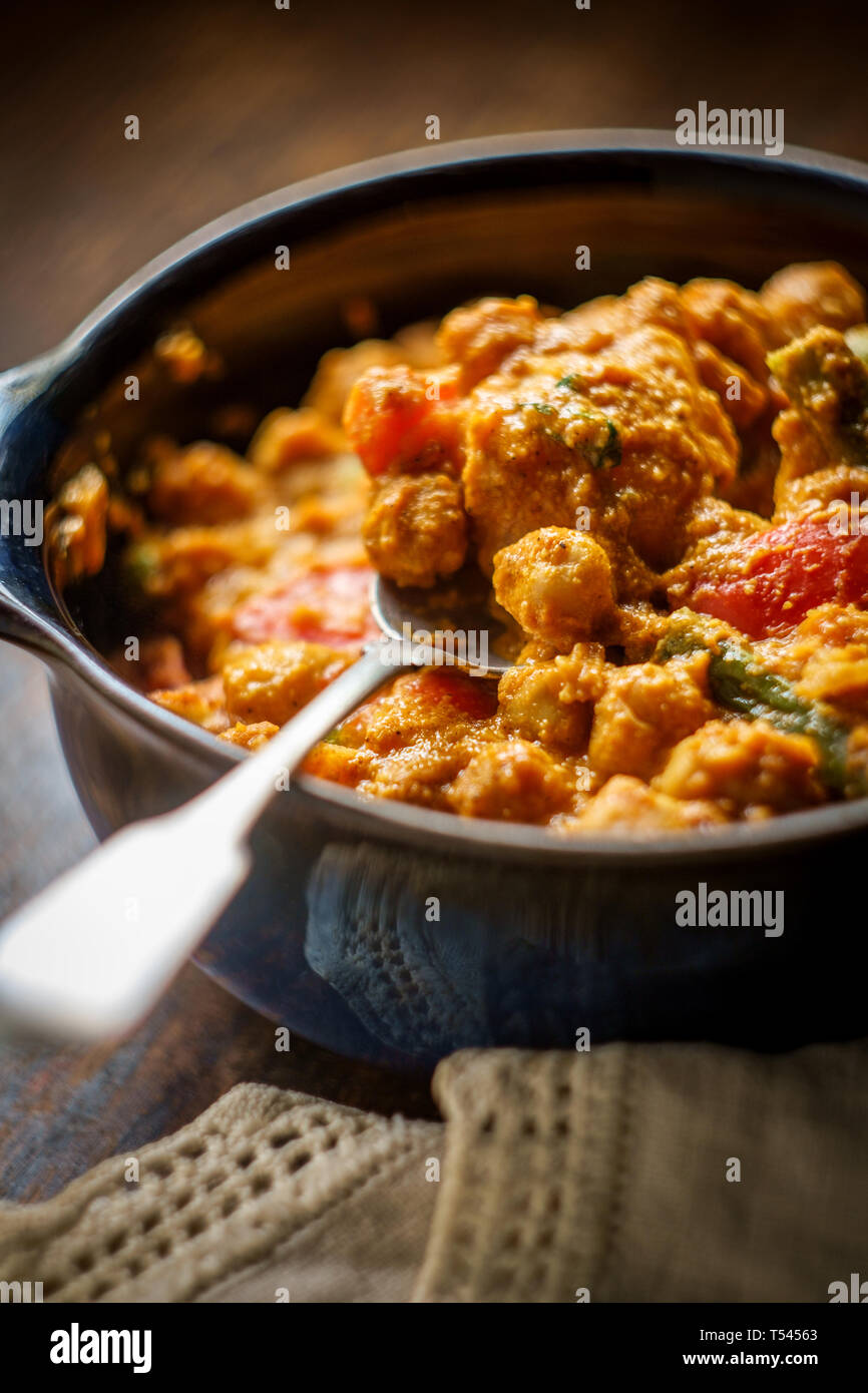 Authentic Indian vegetarian chickpea curry also called Navratan korma with rustic dark and moody