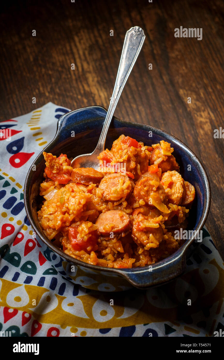 Creole bowl of chicken and andouille sausage Jambalaya with rice in dark moody rustic kitchen