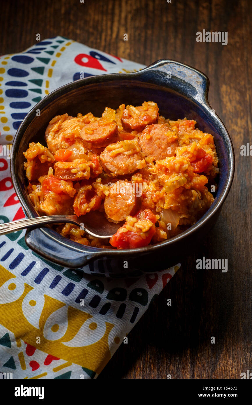Creole bowl of chicken and andouille sausage Jambalaya with rice in dark moody rustic kitchen