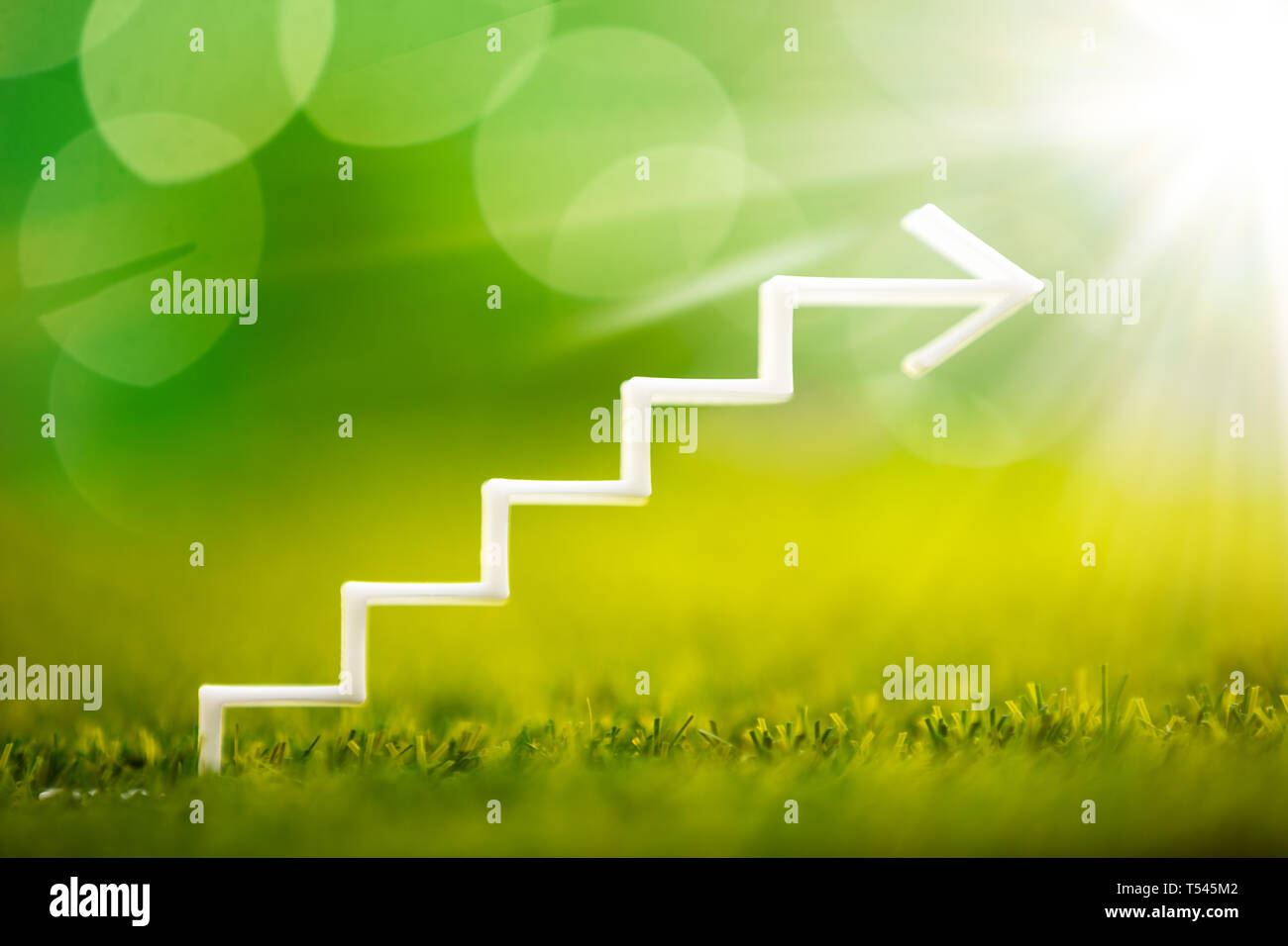 Close-up Of White Increasing Staircase Arrow On Grass Stock Photo