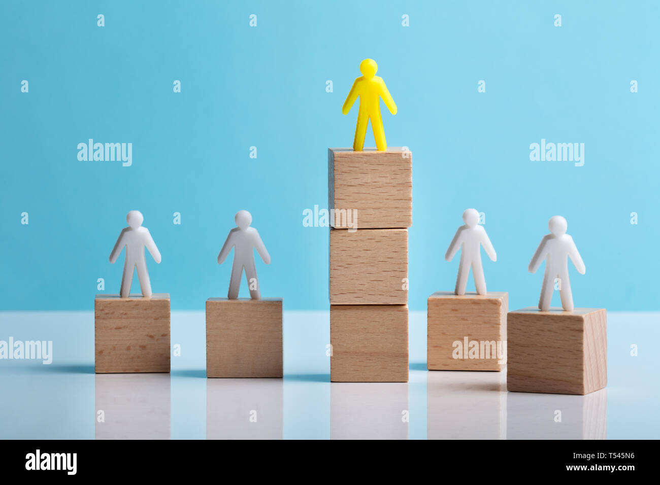 Human Dummy Figure On Wooden Block Over The White Desk Against Blue Background Stock Photo
