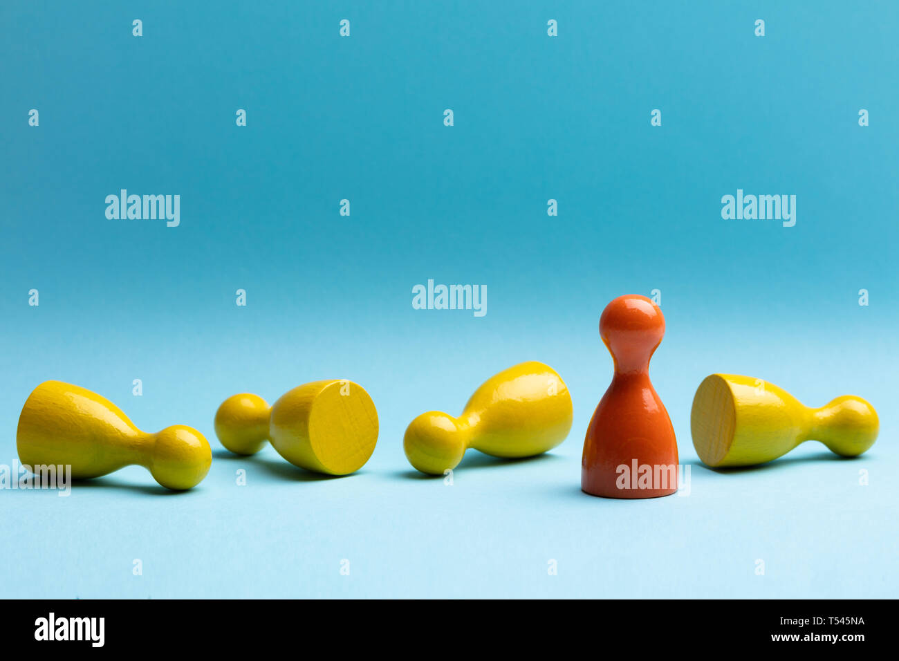 Red Standing Pawn With Fallen Yellow Pawn On Blue Surface Stock Photo