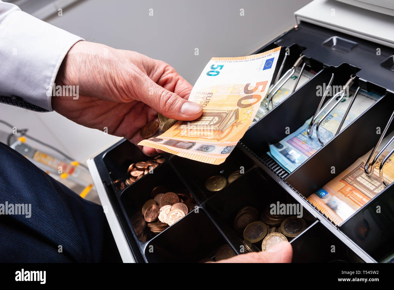 An Overhead View Of Cashier's Hand Taking Banknote From Opened Till Stock Photo