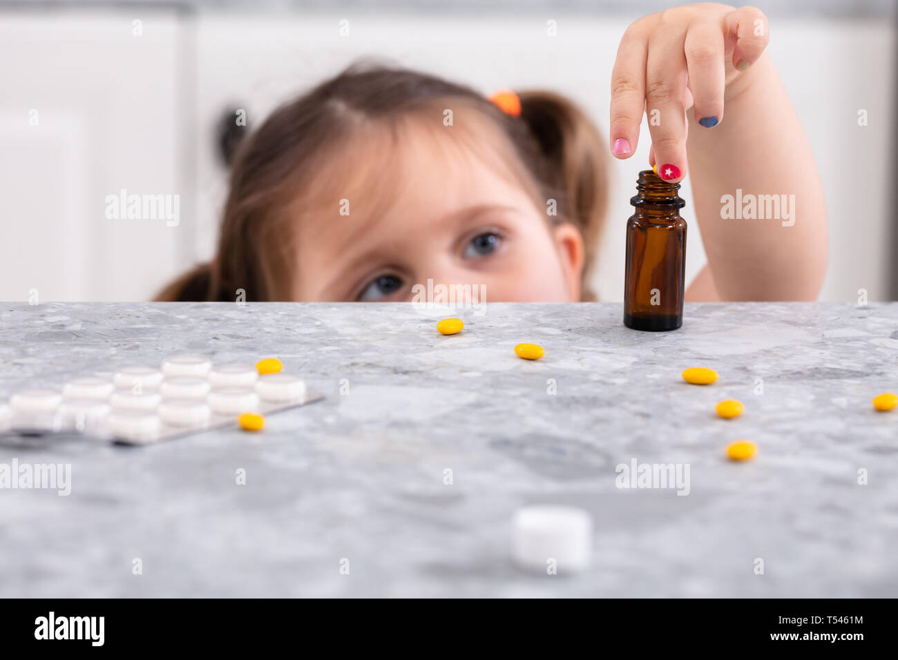 Cute Little Girl Trying To Take Pills On Marble Worktop Stock Photo - Alamy