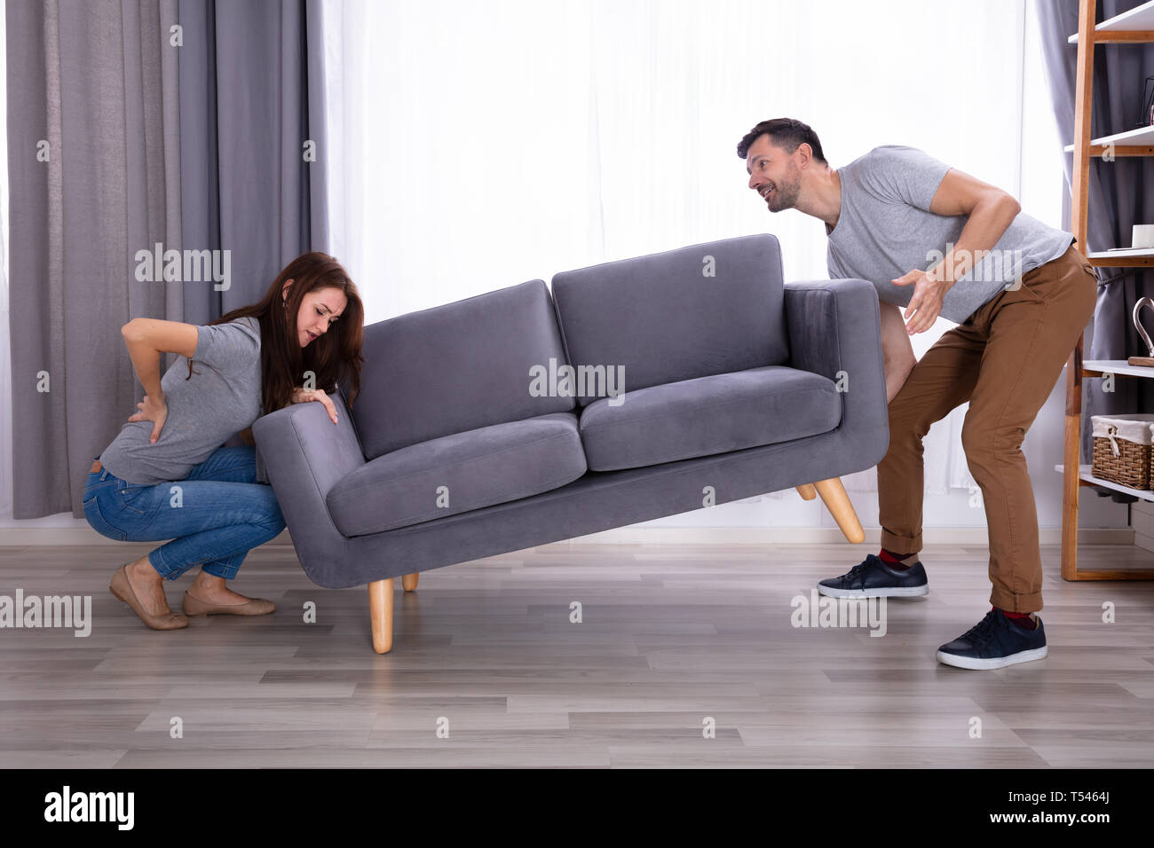 Young Man Looking At His Wife Suffering From Back Pain While