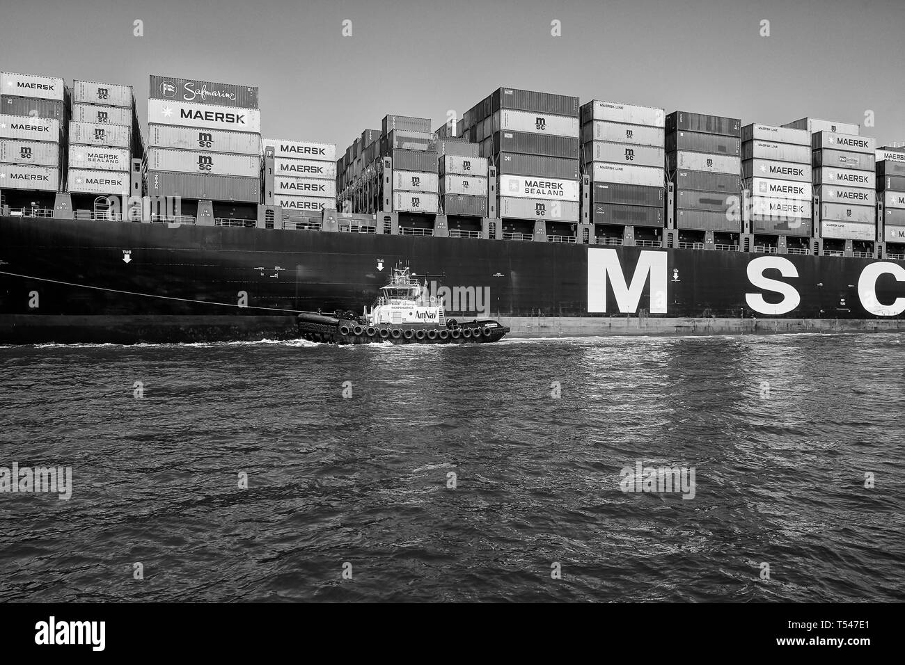 Black And White Photo Of The AmNav Tractor Tug (Tugboat), INDEPENDENCE, Guiding The Container Ship, MSC ELODIE In The Port Of Long Beach, USA. Stock Photo