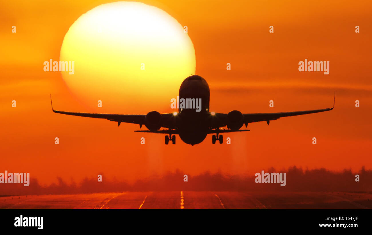 Airliner taking off at sunrise, passing the sun Stock Photo