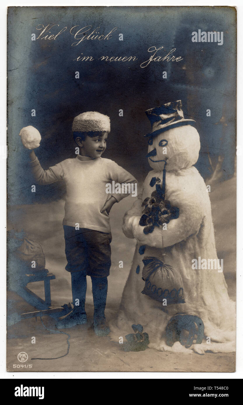 Boy and snowman depicted in the vintage Austrian New Year postcard issued before 1912. Text in German means: Good luck in the New Years (Viel Glück im Neuen Jahre). Courtesy of the Azoor Postcard Collection. Stock Photo