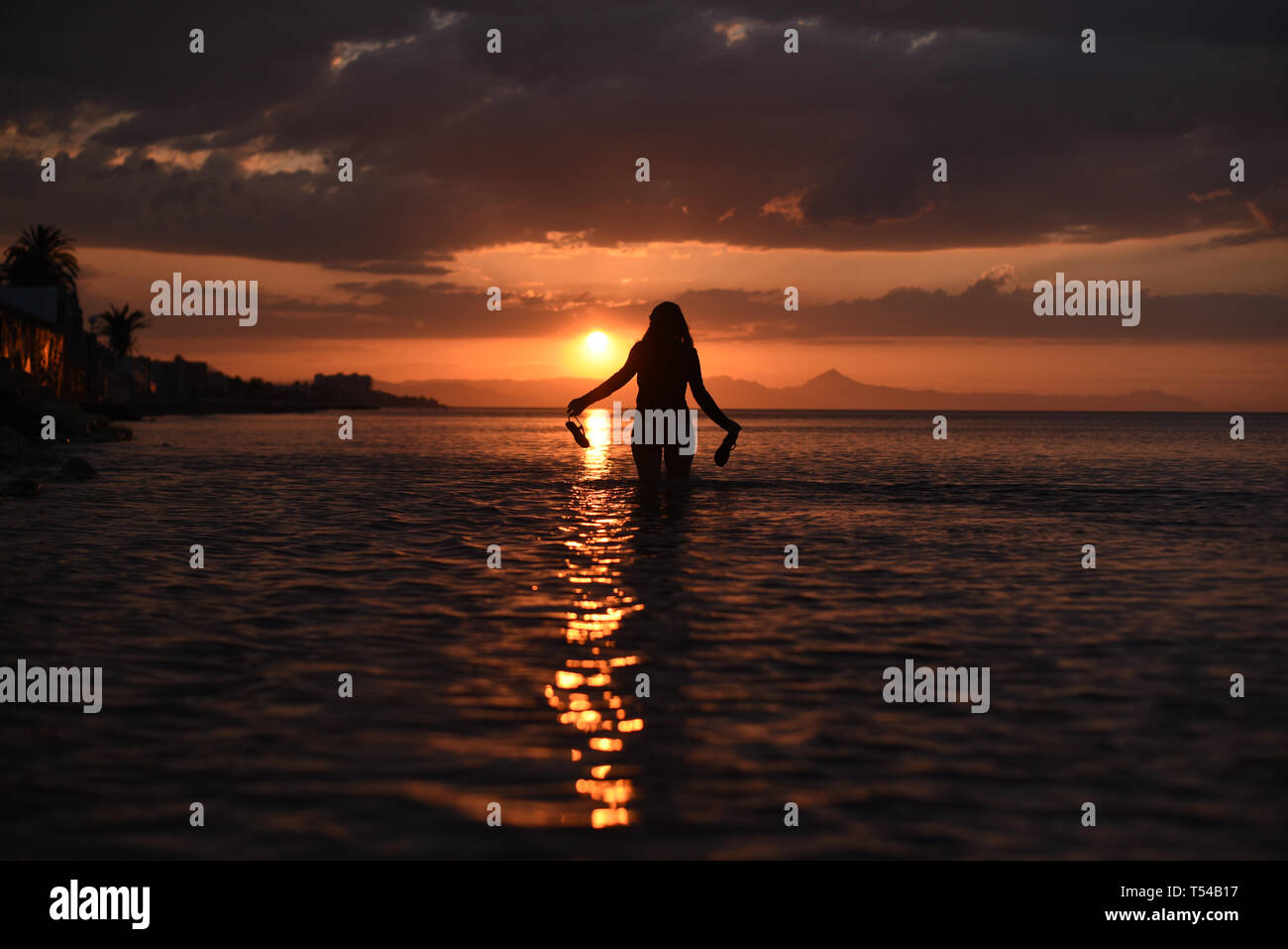 the figure of a woman walking on the beach during sunset Stock Photo ...