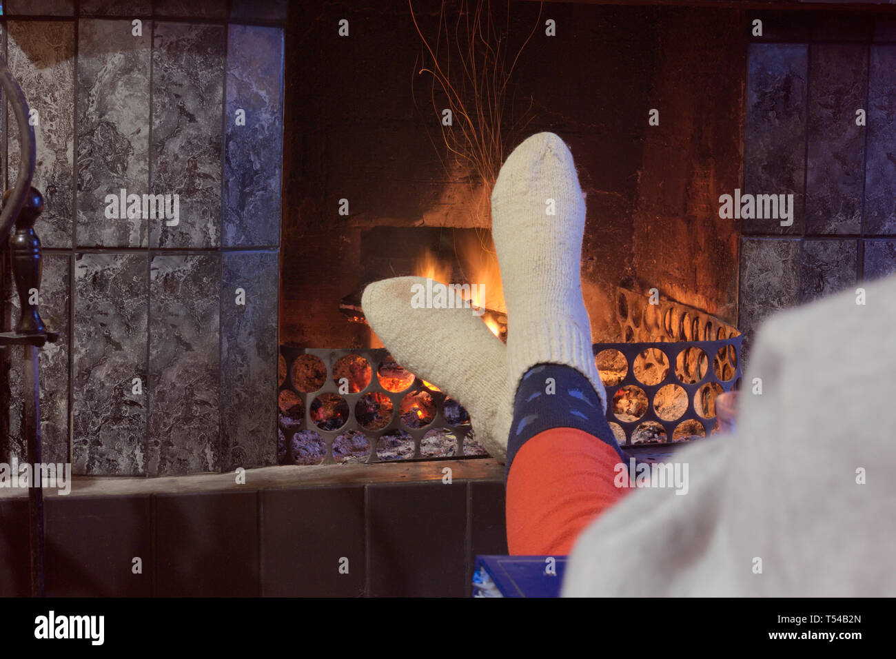 Feet in woollen socks by the fireplace Stock Photo