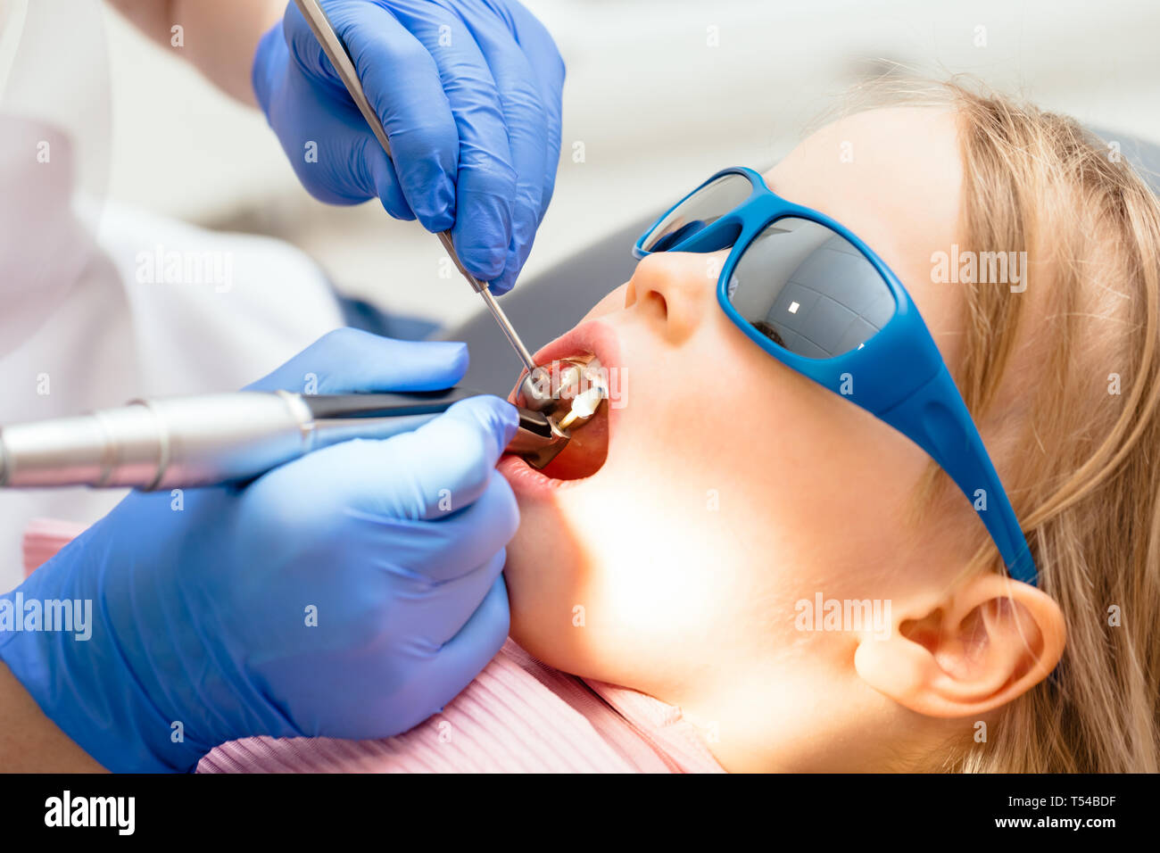 Dentist performing dental procedure to a little girl in pediatric