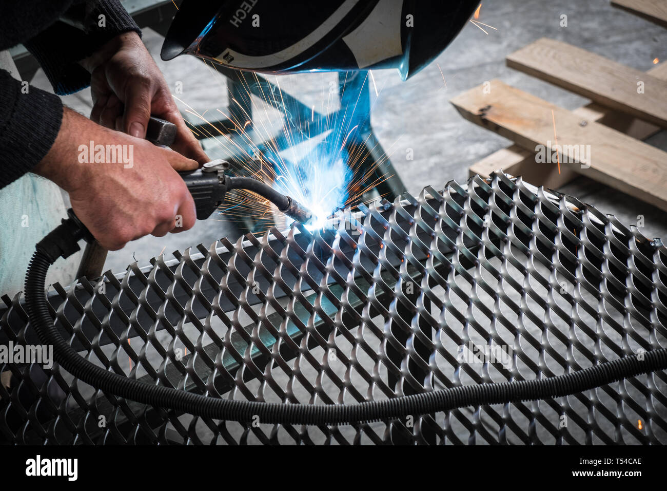 Worker welding steel mesh to the frame with MIG technology Stock Photo