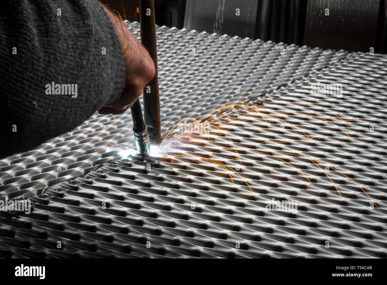 Worker welding steel mesh to the frame with MIG technology Stock Photo