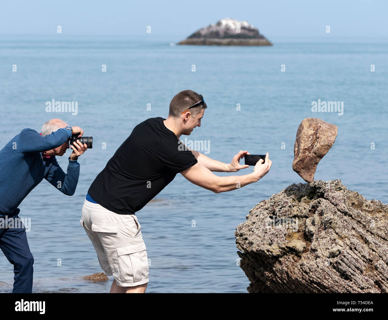 Dunbar, Scotland, UK. 20th Apr, 2019. Photographers take photos of solitary stone balanced in rock on Eye Cave beach in Dunbar during opening day of the European Stone Stacking Championship 2019. Credit: Iain Masterton/Alamy Live News Stock Photo