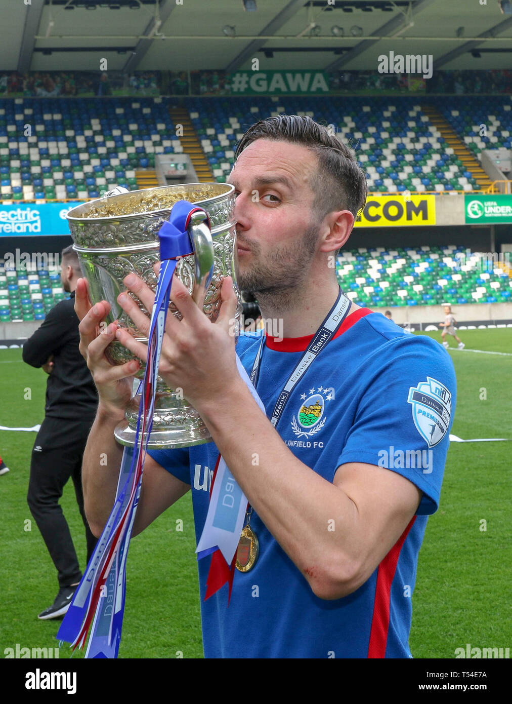 Windsor Park, Belfast, Northern Ireland, UK. 20th Apr, 2019. Linfield, confirmed as Danske Bank Premiership champions last Saturday, lifted the league trophy today after their home league game against Glenavon. The Belfast side, managed by former Northern Ireland international David Healy, have now won the Irish League title on 53 occasions. Andrew Waterworth with the cup. Credit: CAZIMB/Alamy Live News. Stock Photo