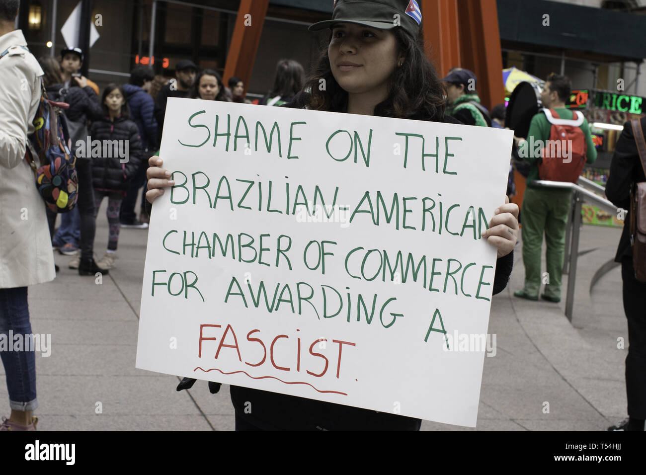 New York, New York, USA. 20th Apr, 2019. GEORGIA KIRILOV holds a protest sign at Zuccotti Park in New York, New York during a demonstration against the Brazilian-American Chamber of Commerce, which later in May, plans to award far-right Brazilian President Jair Bolsonaro the 'man of the Year Award.''.Earlier this month The American Museum of Natural History in New York has announced that it will not host the event honoring Bolsonaro because of his outspoken desire to roll back environmental protections Credit: Brian Branch Price/ZUMA Wire/Alamy Live News Stock Photo