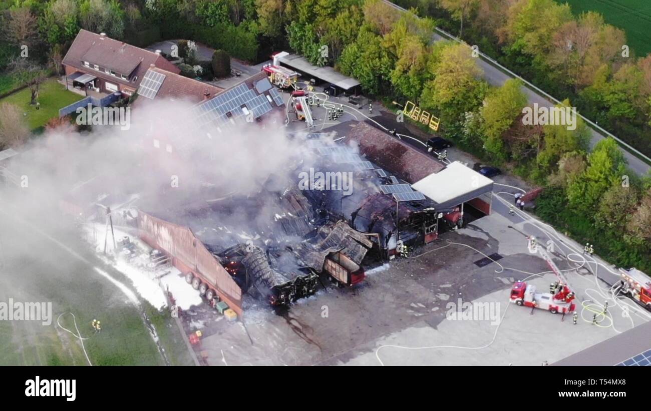 Senden, Germany. 21st Apr, 2019. Fire trucks stand next to a burned-down warehouse. A fire severely damaged the hall of an agricultural company in the Münsterland region. According to police, the operator of the hall expects damage of several million euros. Credit: -/Nord-West-Media TV/dpa - ATTENTION: best possible quality/dpa/Alamy Live News Stock Photo