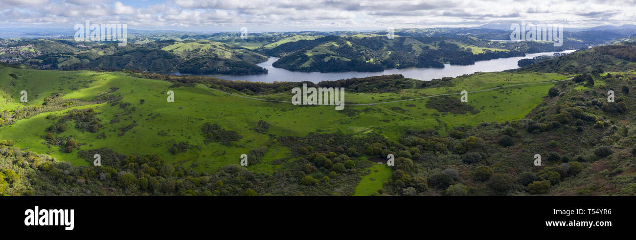 A beautiful morning lights the green hills around the San Pablo Reservoir in Northern California. A wet winter has caused lush vegetation growth. Stock Photo