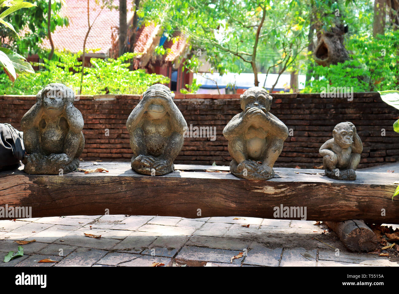 Three monkey statue sit on nature background and hand small statues with the concept of see no evil, hear no evil and speak no evil Stock Photo