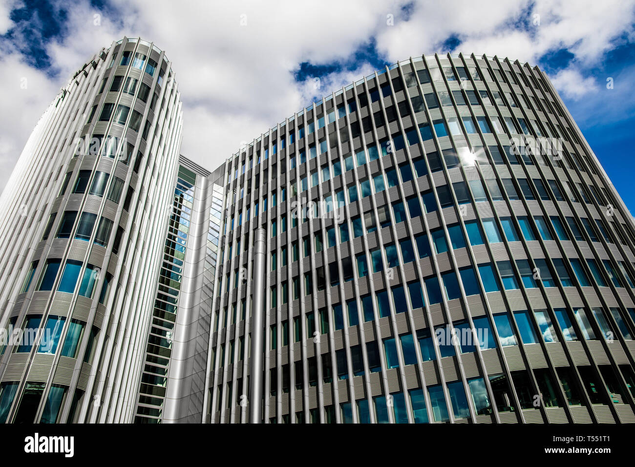 A fragment of the  modernmulti-window building on the background of a cloudy sky on a sunny summer day. Stock Photo