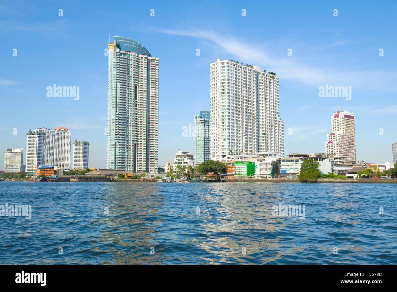 BANGKOK, THAILAND - JANUARY 01, 2019: Modern high-rise buildings on the bank of the Chao Phraya River on a sunny afternoon Stock Photo