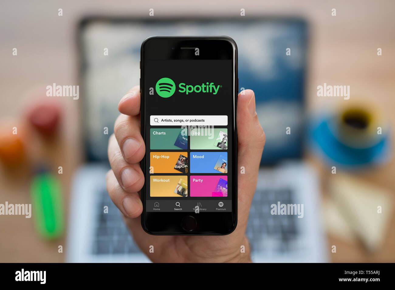 A man looks at his iPhone which displays the Spotify logo (Editorial use only). Stock Photo