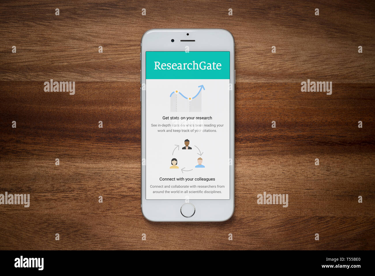 An iPhone showing the Research Gate website rests on a plain wooden table (Editorial use only). Stock Photo