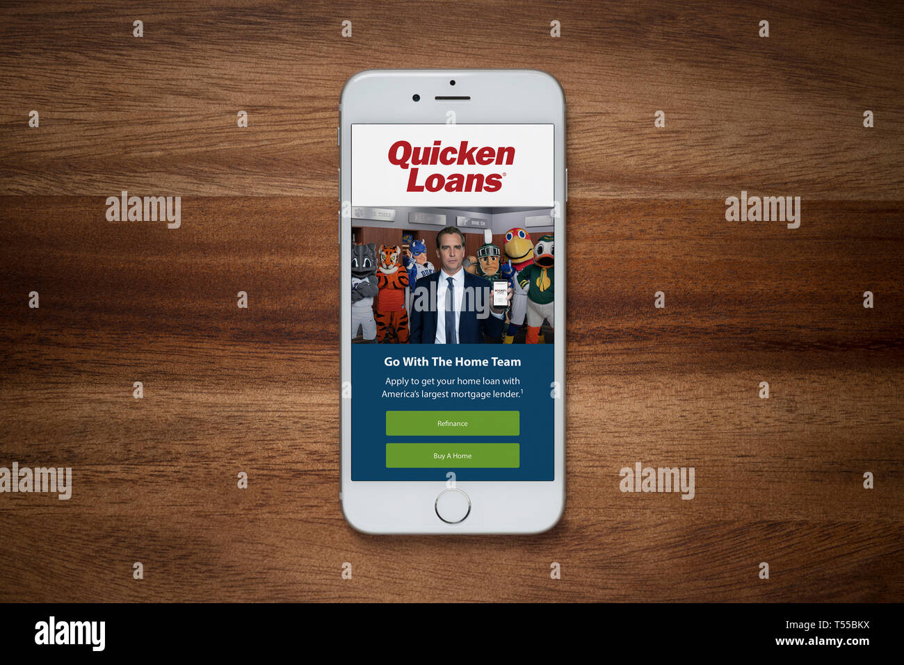 An iPhone showing the Quicken Loans website rests on a plain wooden table (Editorial use only). Stock Photo