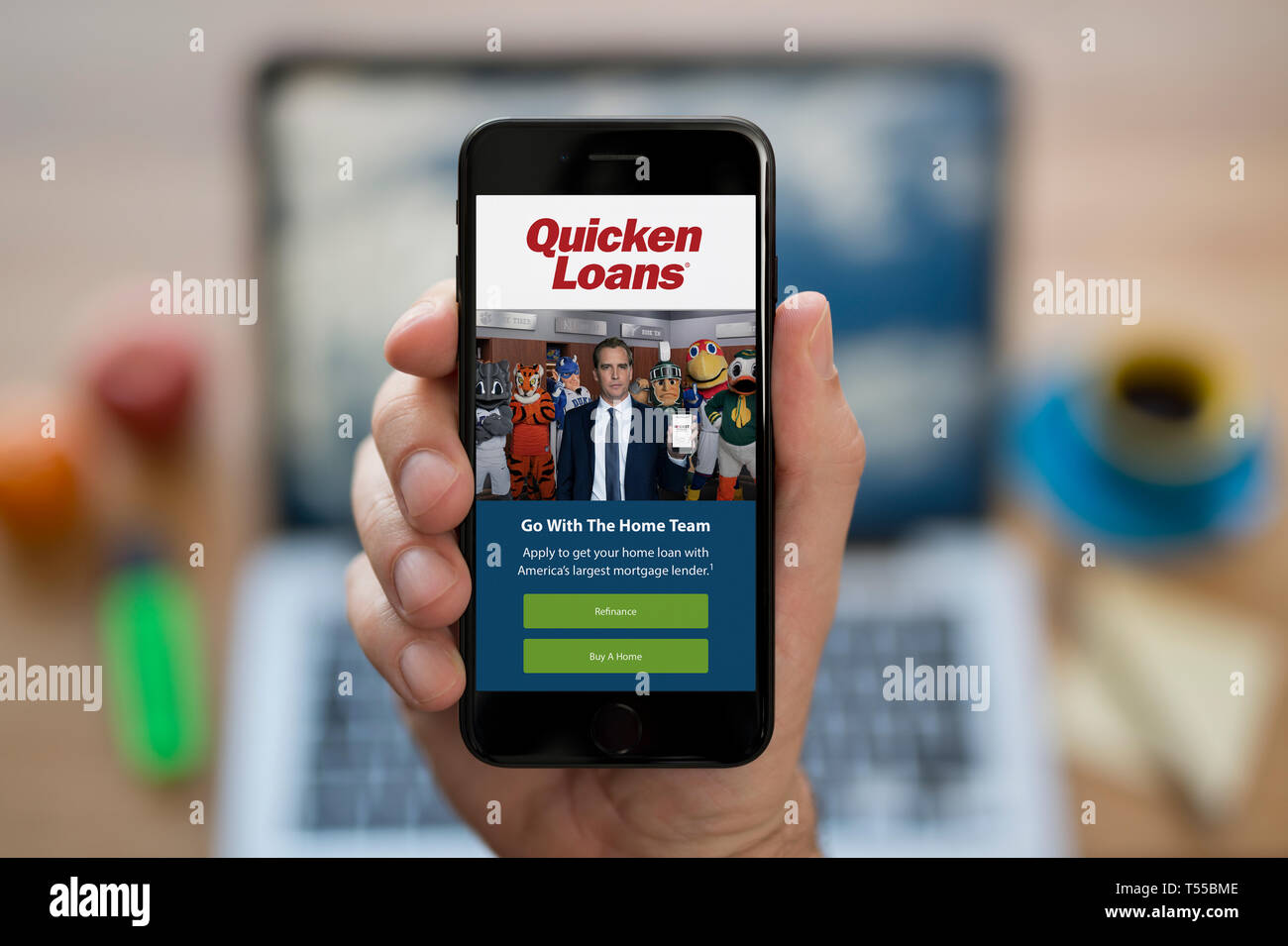 A man looks at his iPhone which displays the Quicken Loans logo (Editorial use only). Stock Photo