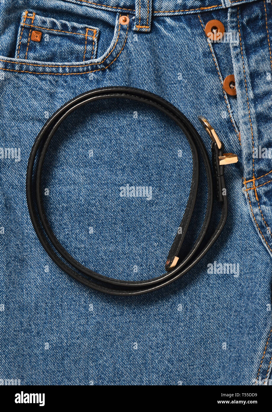 Black leather belt on jeans. Top view. Trend of minimalism Stock