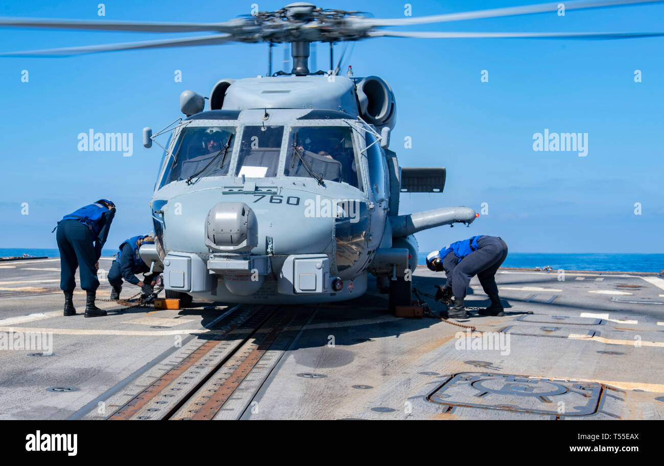 190418-N-XN169-1018 MEDITERRANEAN SEA (April 18, 2019) Sailors secure an MH-60R Sea Hawk helicopter assigned to the “Grandmasters” of Helicopter Maritime Strike Squadron (HSM) 46 to the flight deck aboard the Arleigh Burke-class guided-missile destroyer USS Mason (DDG 87). Mason is underway as part of Abraham Lincoln Carrier Strike Group’s (ABECSG) deployment in support of maritime security cooperation efforts in U.S. 5th, 6th and 7th Fleet areas of responsibility. With Abraham Lincoln as the flagship, deploying strike group assets include staffs, ships and aircraft of Carrier Strike Group 12  Stock Photo