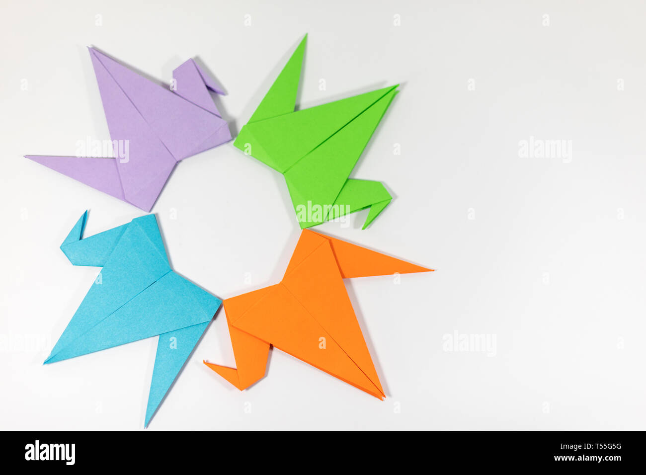 Hand folded bright coloured origami paper cranes arranges in a circular pattern isolated on a white background Stock Photo