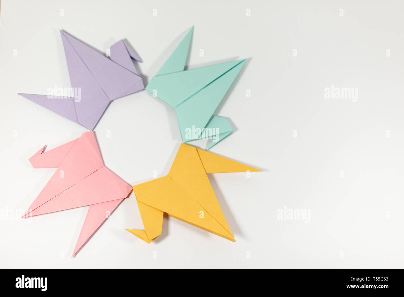 Hand folded pastel coloured origami paper cranes arranges in a circular pattern isolated on a white background Stock Photo