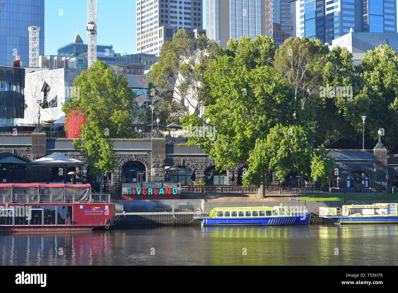 Riverland bar and cafe on bank of Yarra River where tourist cruise boats park with skyscrapers in background. Stock Photo