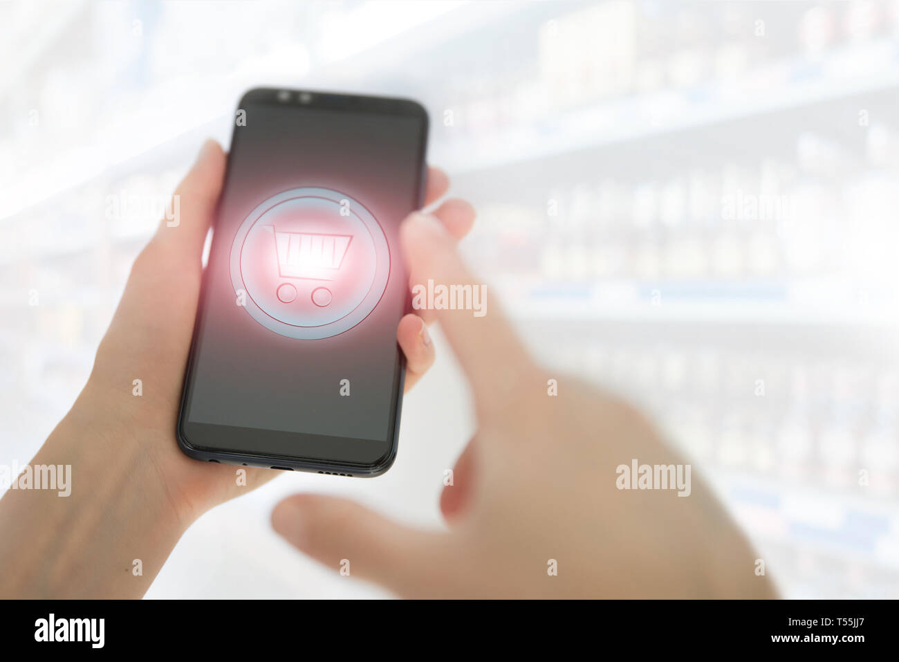 Shopping basket on a mobile phone screen. Woman Hand holding mobile phone on Supermarket blur background Stock Photo