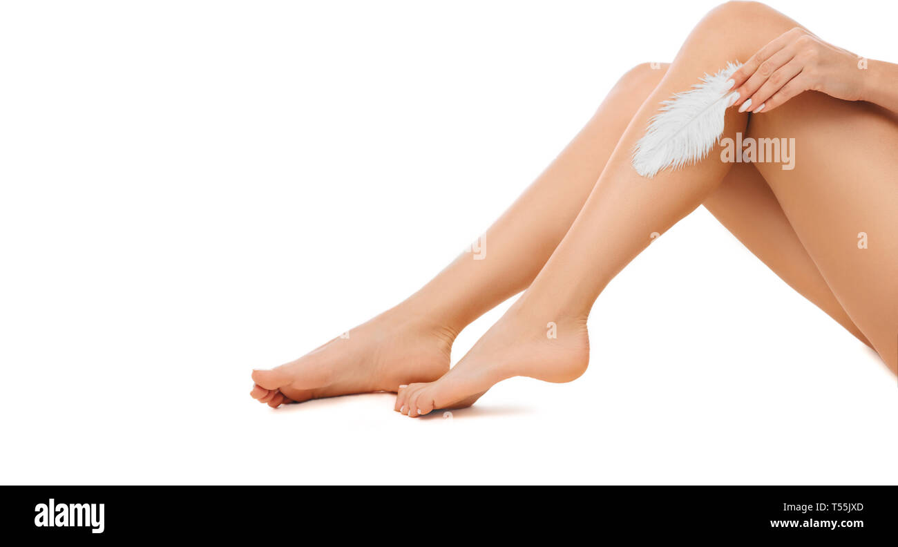 woman touching with feather to her shiny smooth skin on legs after hair