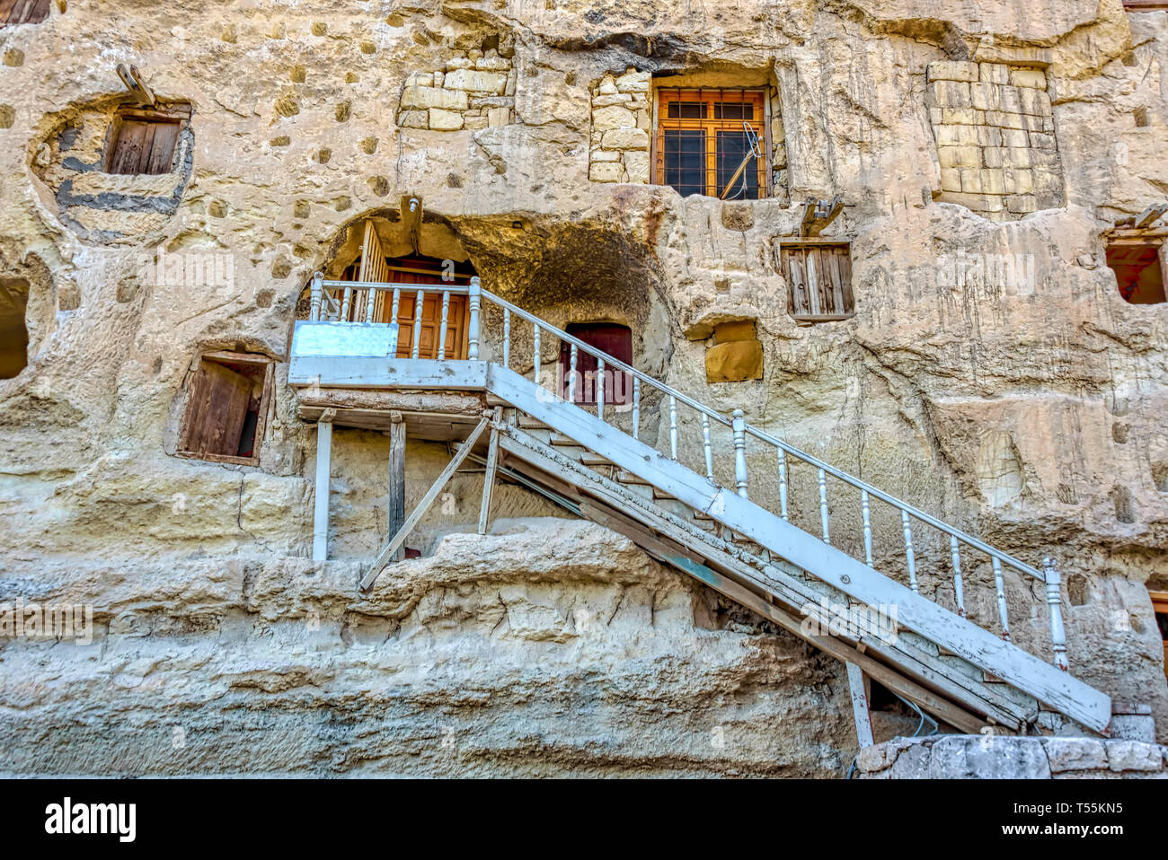 White iron stairs leading to one of the naturally  cool, stone carved warehouses along with many pigeon lofts for manure on a limestone cliff in Ermen Stock Photo
