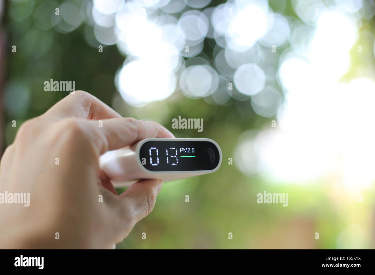 measuring outdoors air quality. A hand holding particulate matter 2.5 (pm.2.5) sensor. harmful small dust detector indicated healthy acceptable air qu Stock Photo