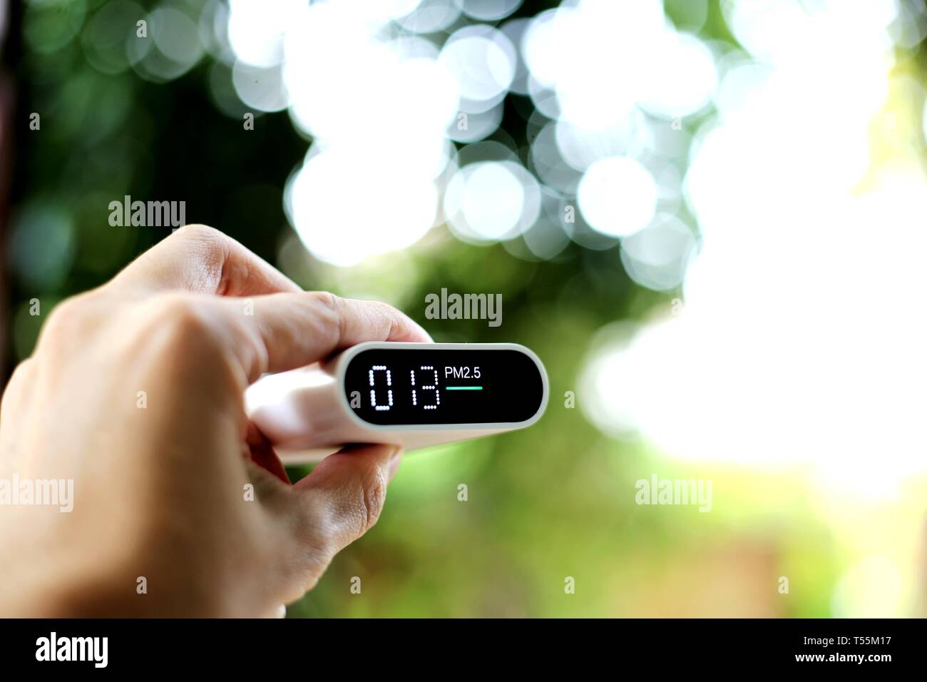 measuring outdoors air quality. A hand holding particulate matter 2.5 (pm.2.5) sensor. harmful small dust detector indicated healthy acceptable air qu Stock Photo