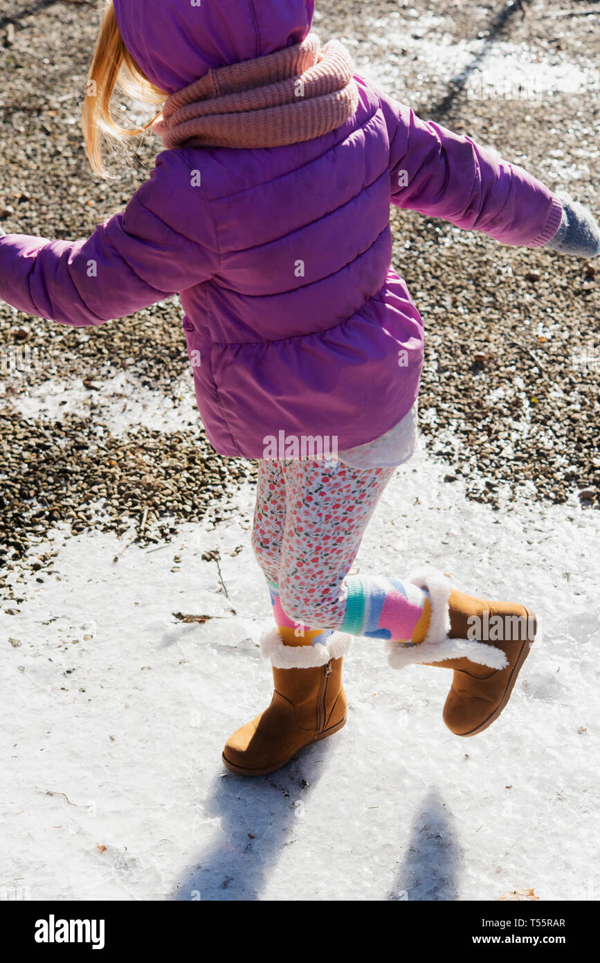 Girl wearing purple coat walking on snow Stock Photo