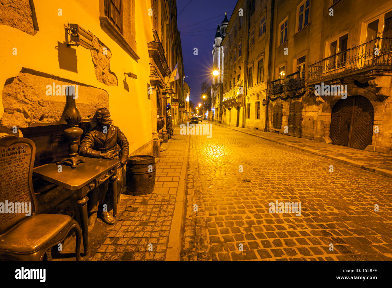 Sculpture of man sitting at table at night in Lviv, Ukraine Stock Photo