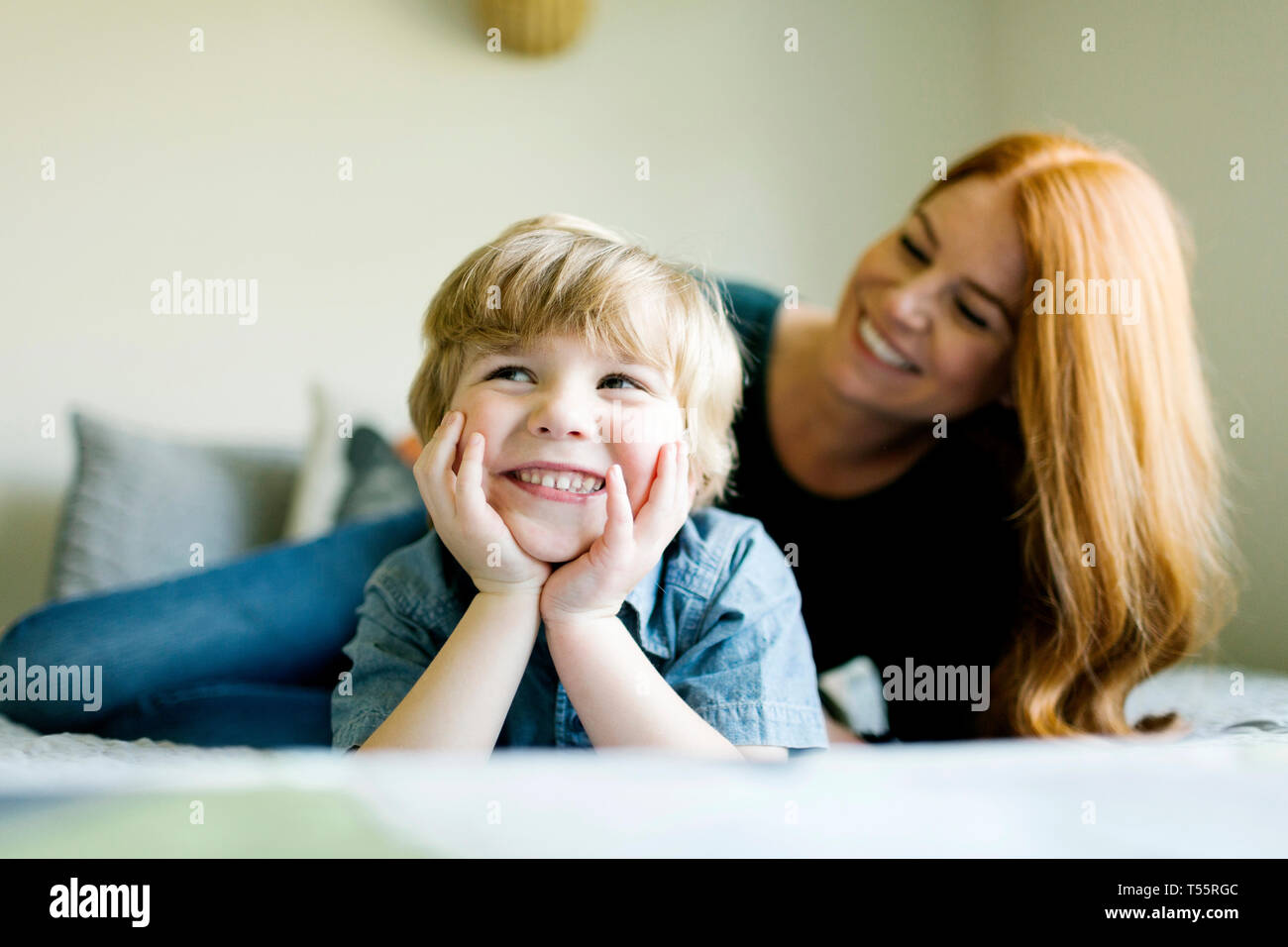 Smiling mother and son lying on bed Stock Photo