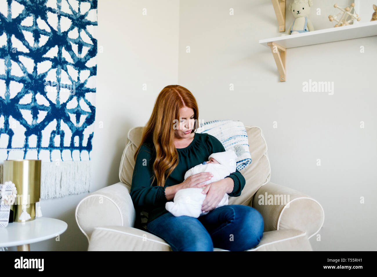 Woman holding her newborn son on armchair Stock Photo